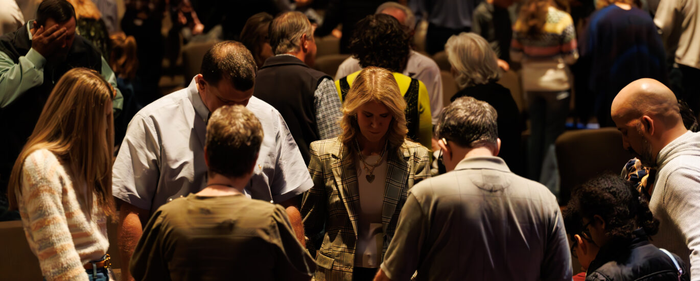 Image of people in a congregation praying with one another.
